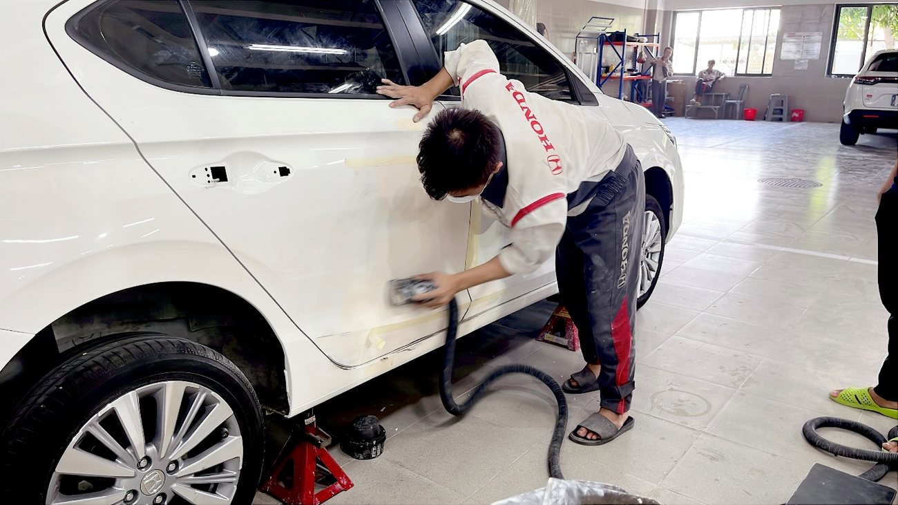 Kỹ thuật viên xử lý bề mặt thân vỏ trước khi sơn